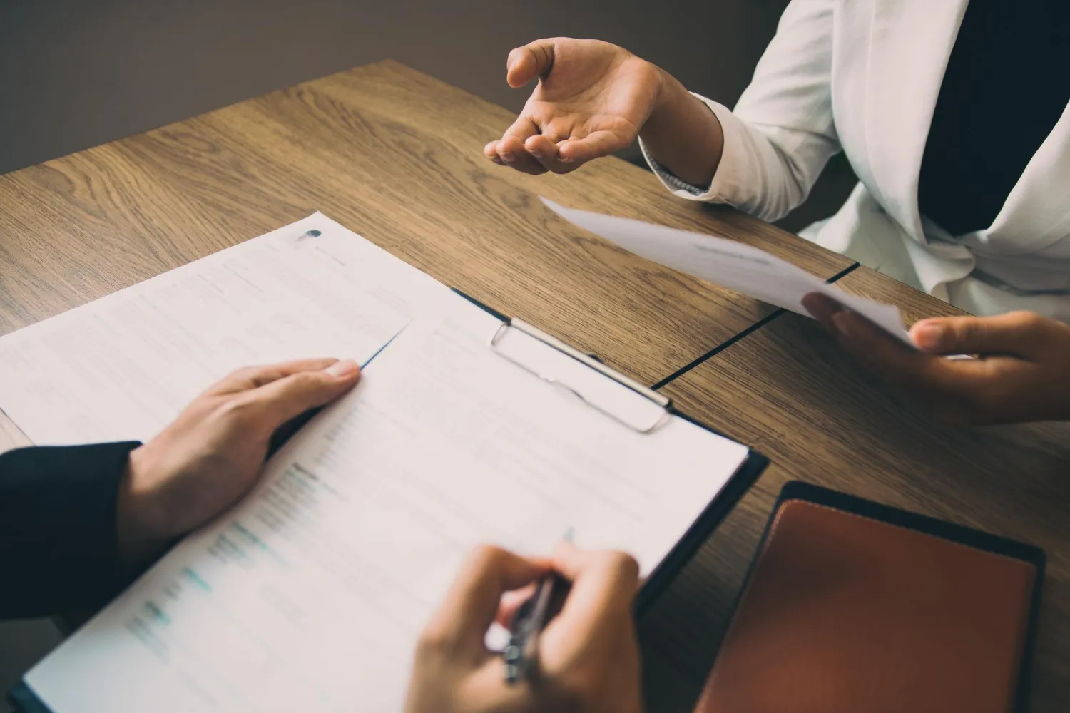 Mãos em reunião discutindo documentos, onde as decisões iniciais definem o resultado de um inventário.